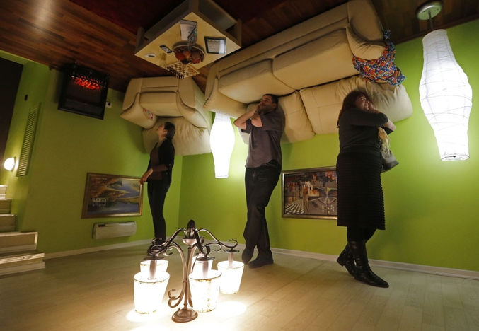 Des visiteurs observent l’exposition d’une maison à l’envers, composée de trois chambres et de deux salles de bain, lors d'une exposition à Saint-Pétersbourg en Russie (photo Alexander Demianchuk pour Reuters)