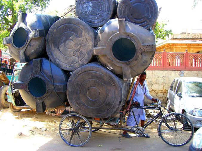 Un type transporte des grosses barriques à vélo.