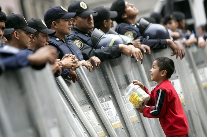 Un enfant propose des bonbon à des policier lors d'une manifestation.