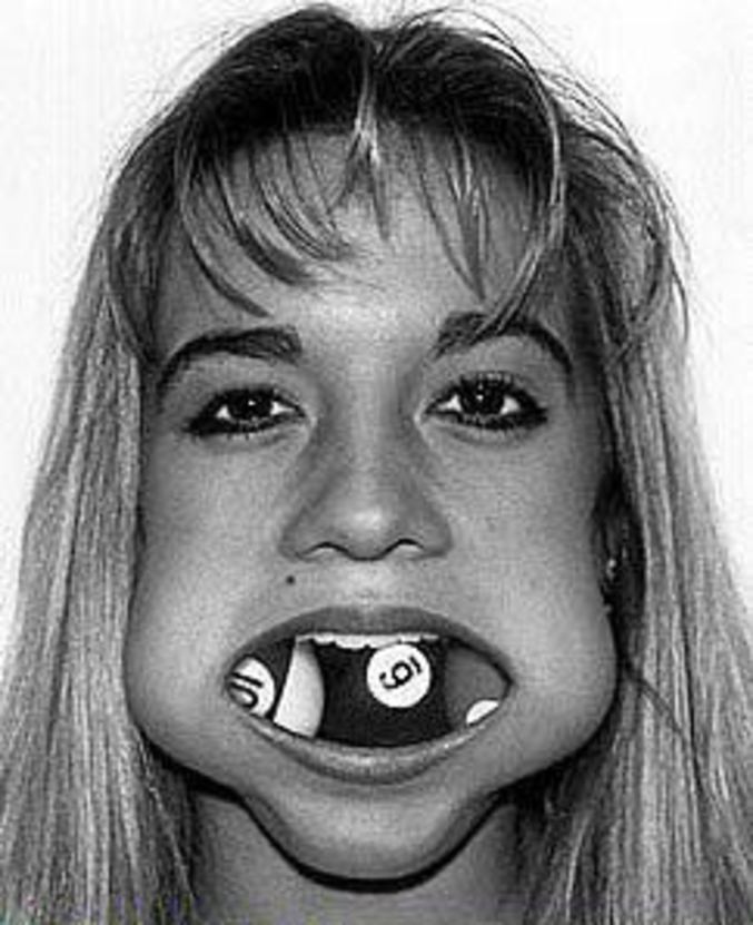 Une jeune femme avec trois boules de billard dans la bouche.