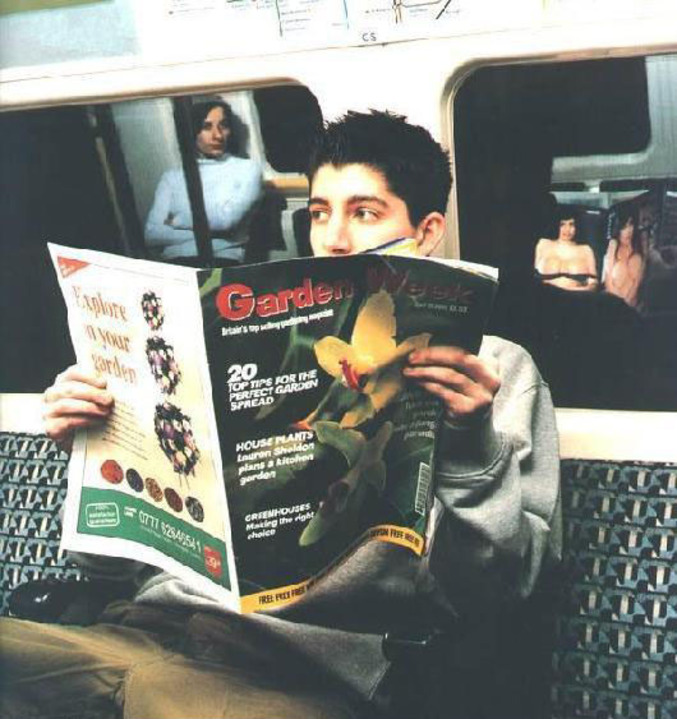 Un jeune homme qui regarde un magazine érotique sous la couverture d'un journal sérieux