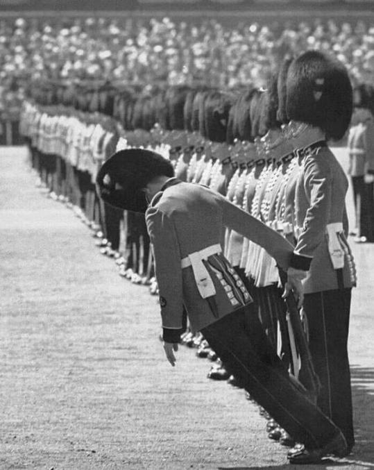 Il n'est pas rare que durant la cérémonie de trooping the colours les soldats, sous leur bonnet à poils et leur uniforme de laine, tournent de l'oeil à cause de la chaleur de Juin. Mais ici, en 1957, le photographe a saisi juste l'instant où le soldat part en digue-digue.