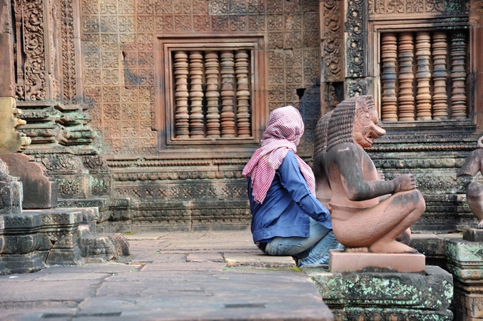 Une femme s'accorde un instant de repos dans un temple bouddhiste, sans savoir qu'elle devient presque l'égal d'un Dieu à côté de ces statues (photo de Louis Foecy).