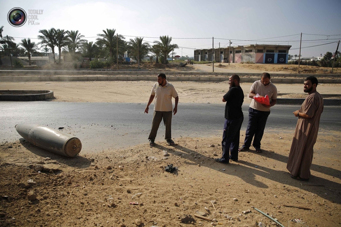 Des Palestiniens regardent une bombe de l'armée israélienne tombée sur la route principale menant à Deir Al-Balah, localité située en plein centre de la Bande de Gaza. La puissance de cette bombe est inconnue mais, le jour où elle est tombée (1er Août), au moins 91 civils palestiniens ont trouvé la mort et plus de 350 ont été blessés, le tout en lien direct avec les bombardements.