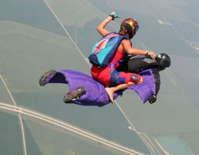 Deux personnes sautent en parachute dans une position assez particulière.