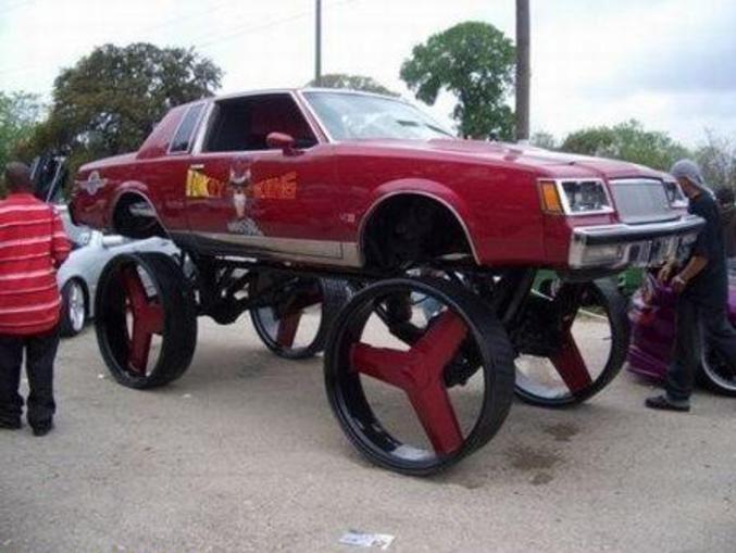 Une voiture surélevée avec des énormes roues sans pneu.