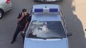 Femme casse un pare-brise de voiture de police