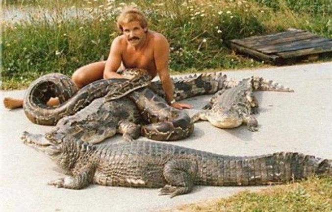 Un homme à l'aise à côté de crocodiles et de serpents.