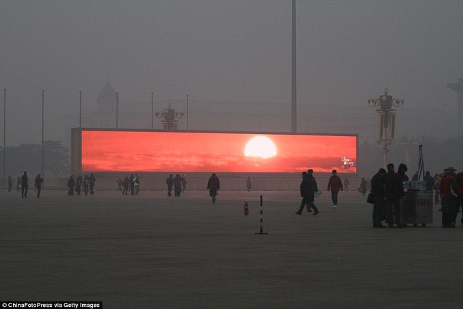 Le 16 janvier 2014, un écran LED affiche le soleil levant sur la place Tiananmen, alors enveloppée dans un lourd brouillard. Le gouvernement municipal de Pékin a publié une alerte pollution ce matin là.