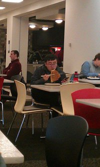 Un asiatique mange une pizza