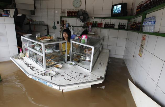 Une femme se tient debout derrière le comptoir de son épicerie dans le quartier des affaires de Jakarta. Il y a un an, les fortes pluies de la mousson avaient déclenché des inondations dans de nombreux quartiers de la capitale indonésienne et provoquant la paralysie des bureaux gouvernementaux et des entreprises du quartier d'affaire faute d'employés. Plusieurs dizaine de milliers d'habitants avaient été forcés de quitter leur domicile. (photo Enny Nuraheni pour Reuters, janvier 2013)