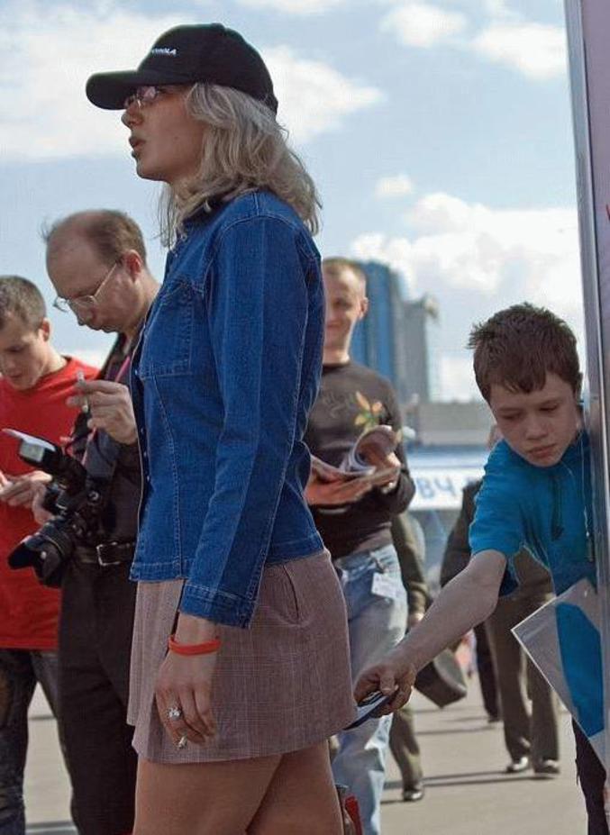 Un enfant prend une photo de la culotte d'une femme avec son portable.