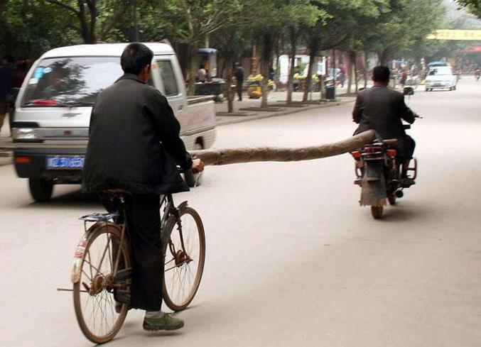 Une manière de transporter un tronc d'arbre en vélo et à moto.