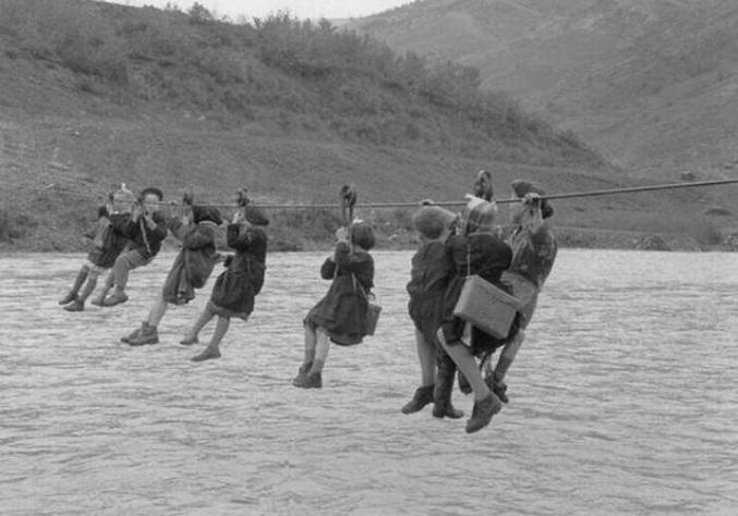 Des enfants traversent la rivière à l'aide de poulies sur le chemin de l'école, 1959, Italie