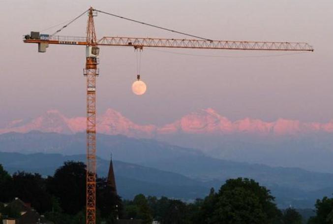 Une illusion qui donne l'impression que la grue empêche le soleil de se coucher.