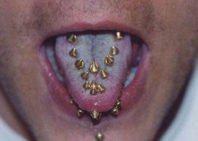 Un homme avec plein de piercings à la langue.
