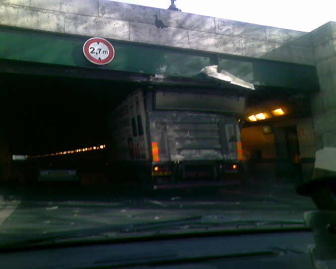 Un conducteur de camion qui ne sait pas lire les panneaux du code de la route sur la hauteur maximale sous un pont.