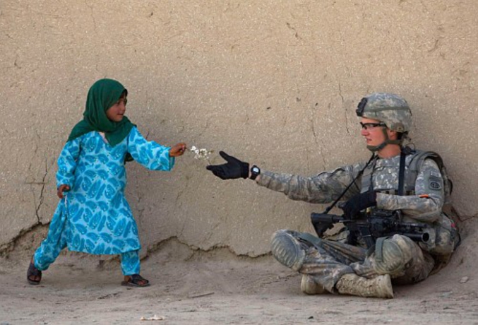 A Kandahar, une jeune-fille afghane offre des fleurs à un soldat étasunien (photo de Baz Ratner pour Reuters, Février 2010)