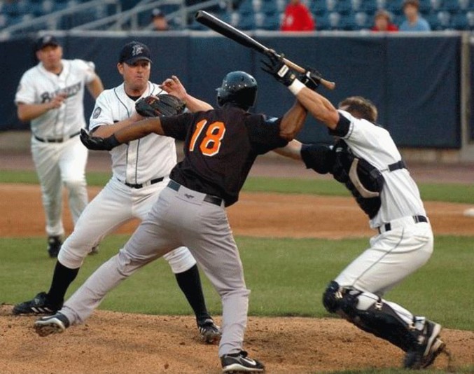 Un joueur de Baseball a l'air de vouloir frapper autre chose qu'une balle avec sa batte.