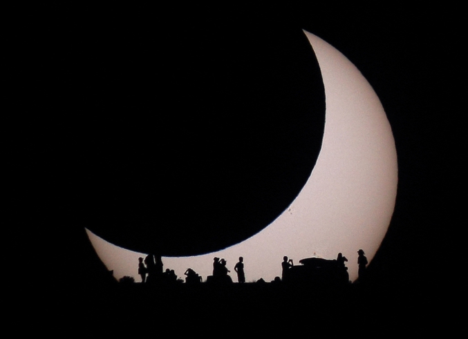 Des silhouettes apparaissent en contre jour lors d'une éclipse de Soleil