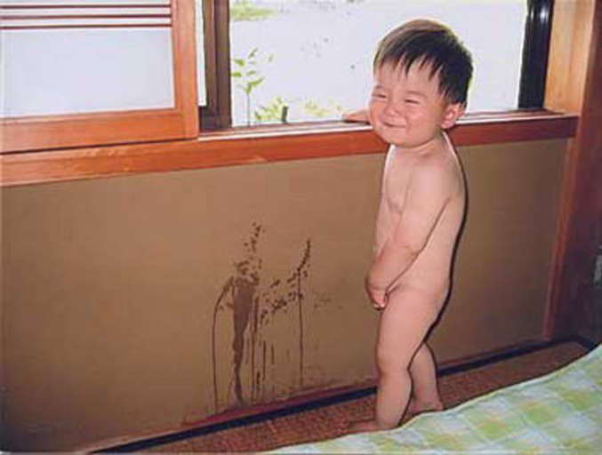 Un petit garçon content de faire pipi sur le mur