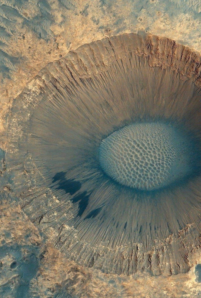 Le ton bleu du fond pourrait être de la glace d'eau qui, gisant sous une fine couche de poussière, aurait été exposée au moment de la collision qui a créé ce cratère de près d'un kilomètre de diamètre.

Photo par la NASA.