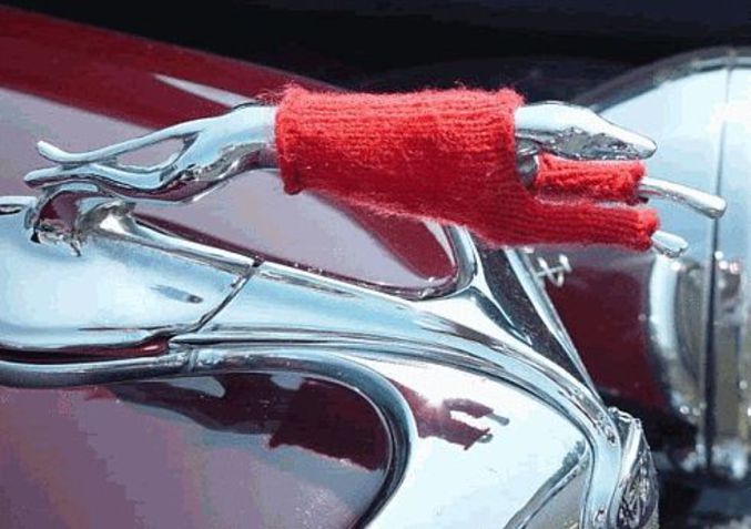 Un petit pull rouge a été enfilé sur une mascotte de voiture.