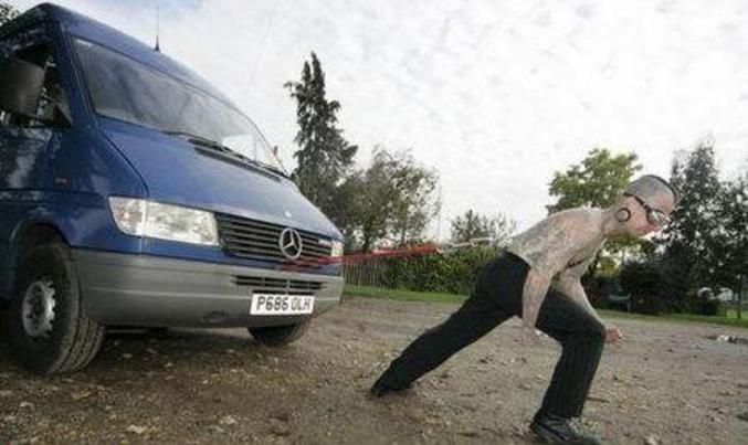 Un type tire un camion grâce à une attache fixée à son dos.