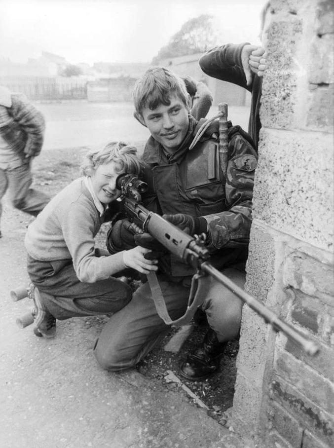 Un soldat britannique permet à un enfant irlandais de regarder dans sa lunette de visée.