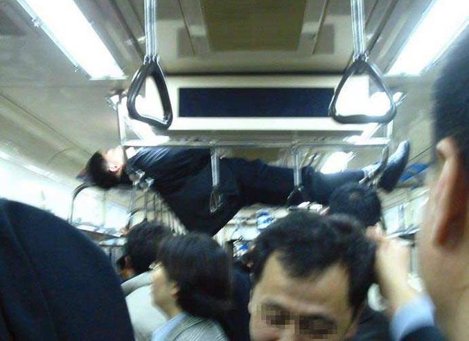 Un homme qui se tient raide et couché au plafond d'une rame de métro