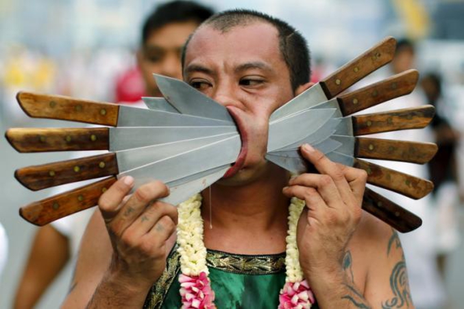Un homme marche avec des couteaux traversant ses joues à Phuket, en Thaïlande, pendant le festival annuel végétarien. (photo de Reuters)
