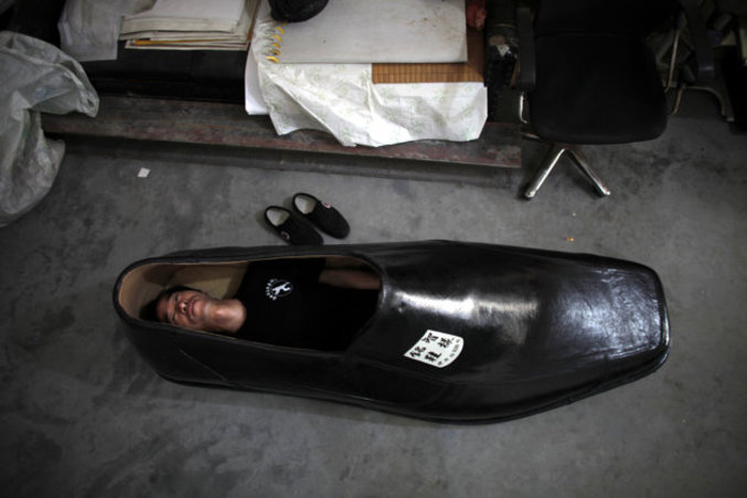 Chen Mingzhi, un créateur de chaussures, allongé à l'intérieur d'un de ses modèles qui mesure 1,90 mètres de long.