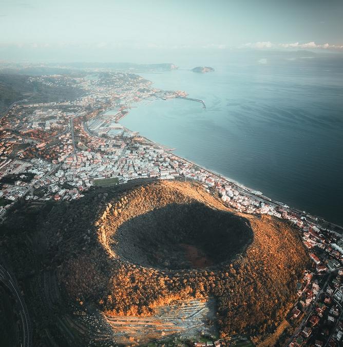 Si c'est bien la silhouette imposante du Vésuve qui s'élève au-dessus de Naples, ce n'est pourtant pas le seul volcan à menacer directement cette grande ville du sud de l'Italie. Car, tapi dans ce doux paysage méditerranéen se cache l’un des supervolcans les plus actifs au monde. Point de cônecône majestueux, mais une vaste caldeiracaldeira dans laquelle ont d'ailleurs élu résidence quelques 360 000 personnes. Seule une vue satellite permet de mesurer la taille du monstre, nommé les champs Phlégréenschamps Phlégréens (Campi Flegrei). Avec 12 à 15 kilomètres de large, la caldeira s'étend en effet au niveau du golfe de Pouzzoles, à seulement 9 kilomètres de Naples. Si une partie est actuellement immergée dans le golfe, le reste se caractérise par la présence de nombreux petits cônes volcaniques. Le plus connu est certainement la Solfatare, vaste cratère d'où s'échappent continuellement fumerolles, gazgaz soufrés et boue bouillonnante, comme pour nous rappeler que le géant n’est qu’assoupi.

Un dangereux géant au sommeil bien léger

Pour les scientifiques en charge de la surveillance du supervolcan, ce sommeilsommeil pourrait d'ailleurs être très léger. Le risque d'une éruption serait même à considérer de manière sérieuse. C'est la conclusion d'une nouvelle étude publiée dans la revue Communications Earth and Environnement.

Impossible de prévoir quand, ni comment les champs Phlégréens pourraient entrer en éruption, mais le volcan est considéré comme particulièrement dangereux. En témoigne la caldeira, qui résulte de deux éruptions majeures survenues il y a 36 000 et 14 000 ans. L'explosion du volcan il y a 36 000 ans est même suspectée d'être en partie responsable de la disparition de l'Homme de NéandertalNéandertal. D'importants dépôts de cendres ont en effet été retrouvés dans toute l'Europe et il est probable que cet épisode ait entraîné un hiver volcanique. La dernière éruption date, quant à elle, du 29 septembre 1538. Cette dernière phase éruptiveéruptive, d'ampleur modérée, s'était soldée par la destruction du village de Tripergole et par la création d'un nouveau mont volcanique de 133 mètres de haut au sein de la caldeira, le monte Nuovo.

Depuis 1950, la région a connu plusieurs petits sursautssursauts d'activité, sans pour autant donner lieu à une véritable éruption. Des dizaines de milliers de petits tremblements de terretremblements de terre ont ainsi été enregistrés depuis, ainsi qu'un soulèvement de la ville de Pouzzoles de près de 4 mètres ! Si, pour l'instant, aucune activité ne laisse présager d'un réveil soudain du volcan, ces petites manifestations pourraient toutefois indiquer que le volcan est en passe d'atteindre son point de rupture.

Une évolution structurale majeure ces dernières années

Ces manifestations sont en effet associées à des mouvementsmouvements de fluides (gaz ou magma) à environ 3 kilomètres sous la surface. La pressionpression qu'exercent ces fluides sur les roches mène d'abord à leur soulèvement puis, lorsqu'elle dépasse un certain seuil, à leur fracturation, ce qui provoque les petits tremblements de terre. Or, depuis 2020, les données suggèrent que les roches ne répondent plus de manière élastique, indiquant une tendance accrue au développement de fractures. La croûtecroûte serait donc de plus en plus fragile et susceptible de rompre facilement si une importante remontée de magma se produisait.

Si les conditions apparaissent donc plus favorables à une éruption, cela ne signifie cependant pas qu'elle va avoir nécessairement lieu. Il peut s'agir en effet d'une petite « crise », à la suite de laquelle le volcan peut tout simplement se rendormir. Ou bien le système peut continuer à évoluer plus ou moins vite vers une éruption. Là encore, impossible de prévoir son ampleur. Il pourrait s'agir de plusieurs petites éruptions, ou d'une éruption majeure, la probabilité de ce dernier cas restant tout de même relativement faible.

Quoi qu'il en soit, le volcan reste sous étroite surveillance, car plusieurs exemples ont révélé que ce type de volcan pouvait entrer brusquement en éruption sans montrer une claire gradation dans les signaux précurseurs, hormis ce passage d'une déformation élastique à un état de rupture.


Source : https://www.futura-sciences.com/planete/actualites/volcan-ce-supervolcan-sud-europe-montre-signes-reveil-105781/