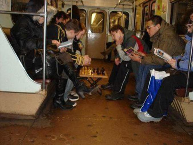 Des hommes jouent au échec pendant leur trajet de métro.