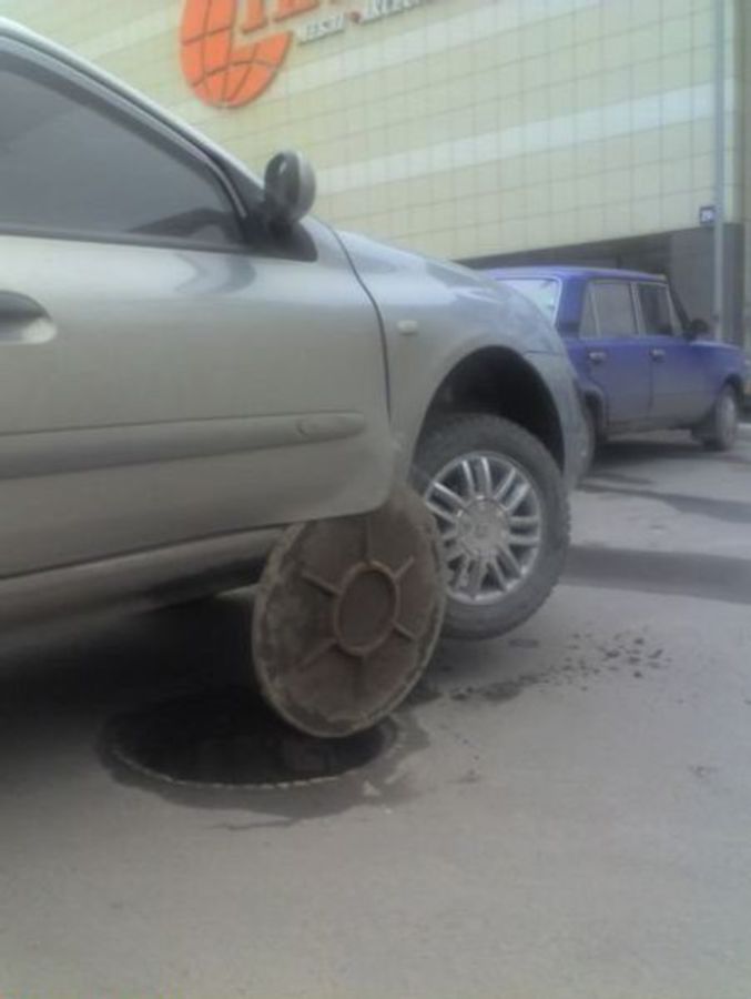 La portière d'une voiture amochée par une plaque d'égout