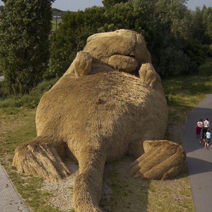 Une marmotte géante en paille se repose au soleil.